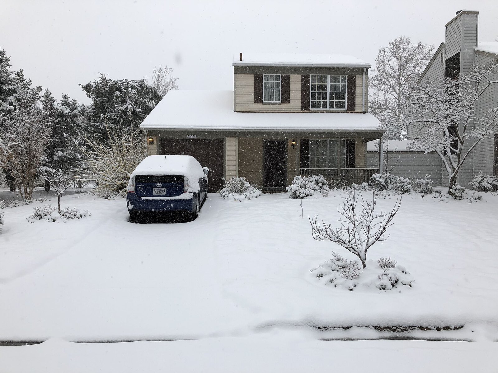 Snow-covered front yard and driveway of a suburban house