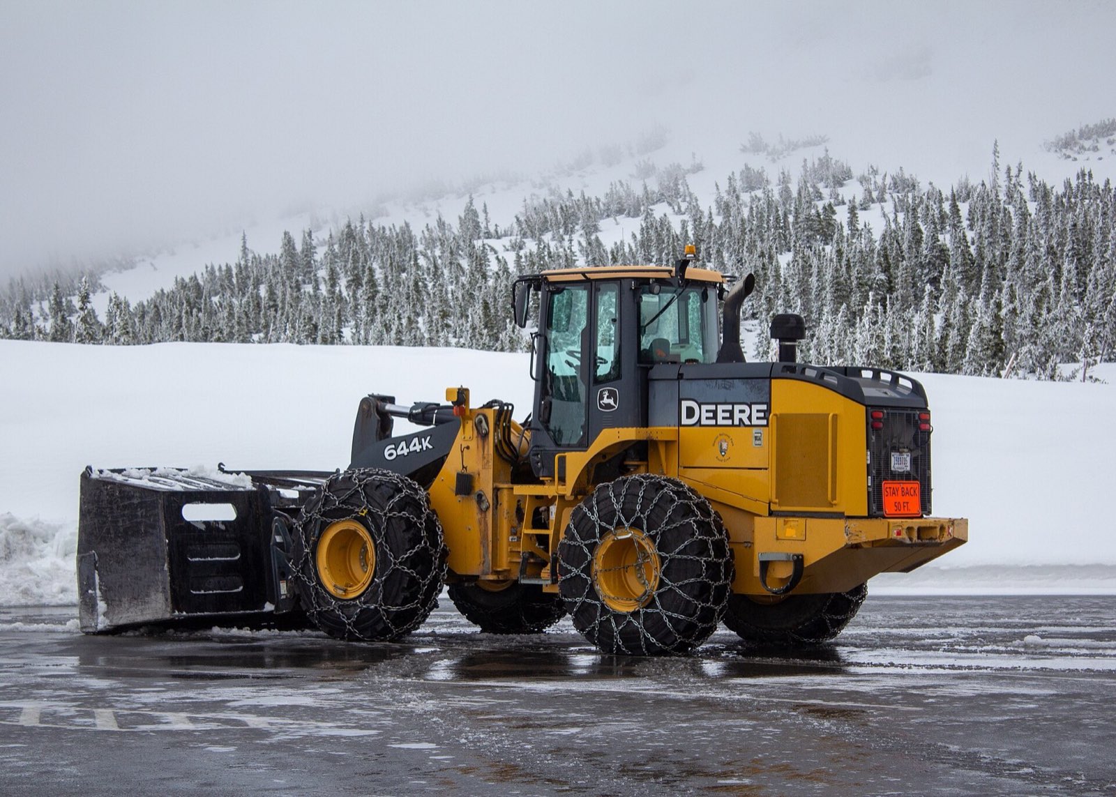 Wheel loader with tire chains ready to push and stack snow