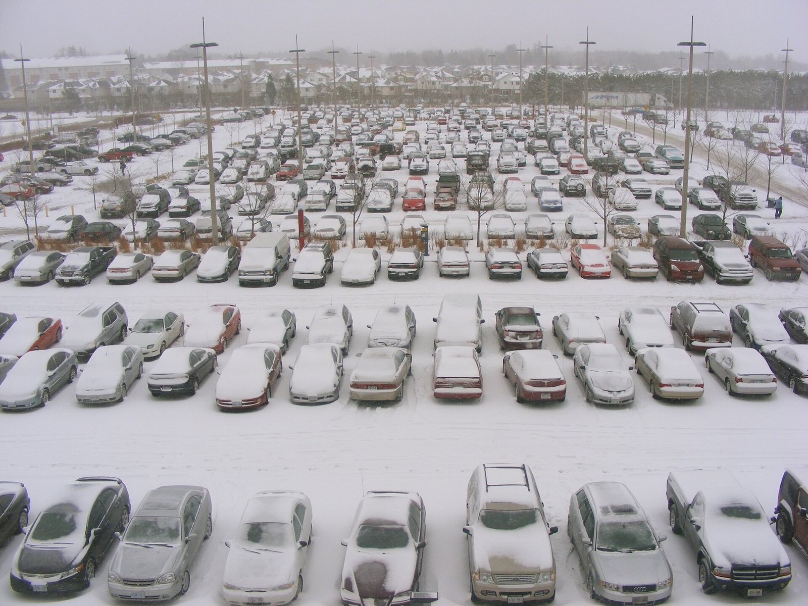 Packed commercial parking lot covered in snow during a storm