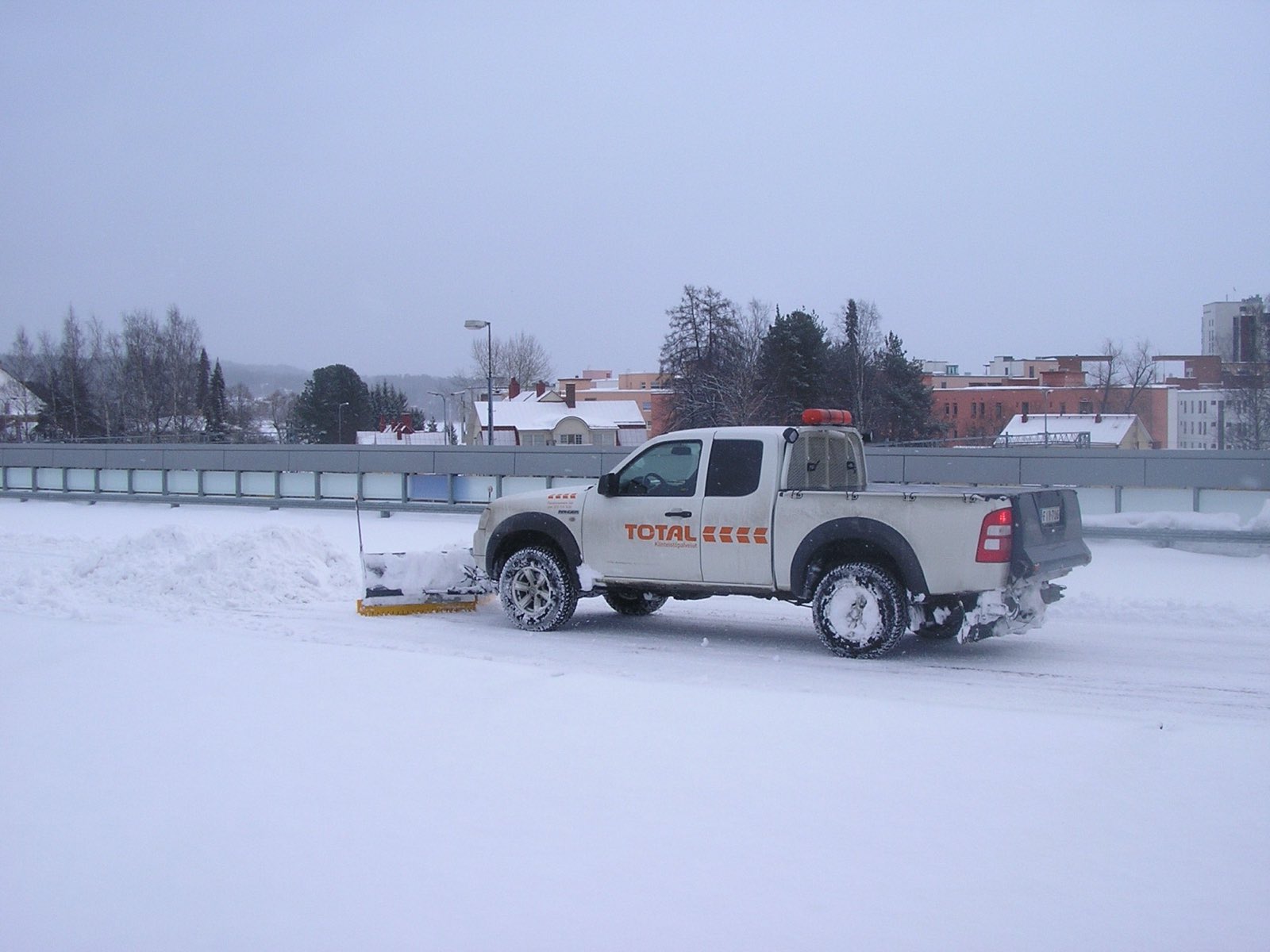 Pickup truck plowing an open lot in winter