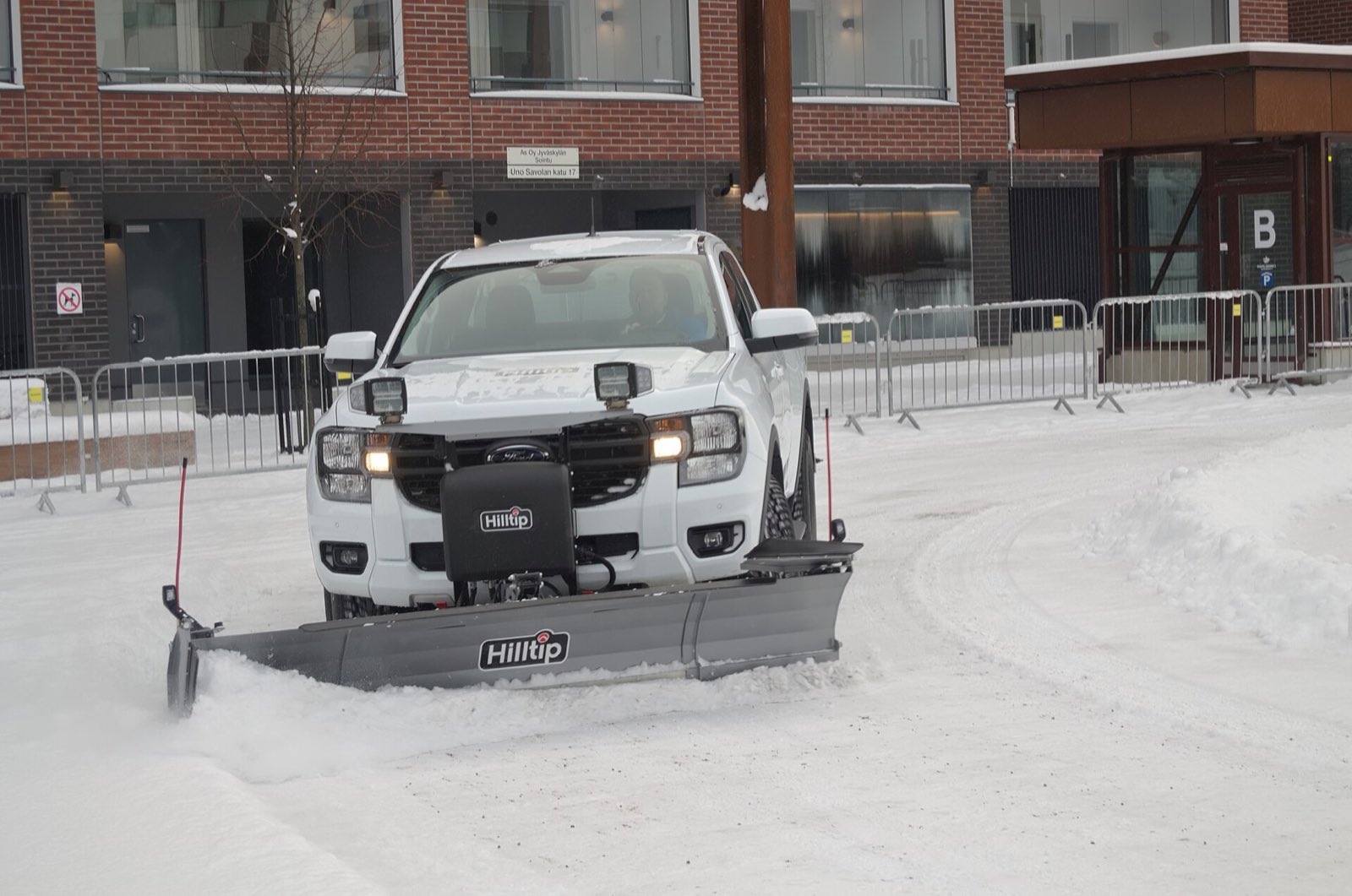 Pickup truck with a straight plow blade clearing a lot