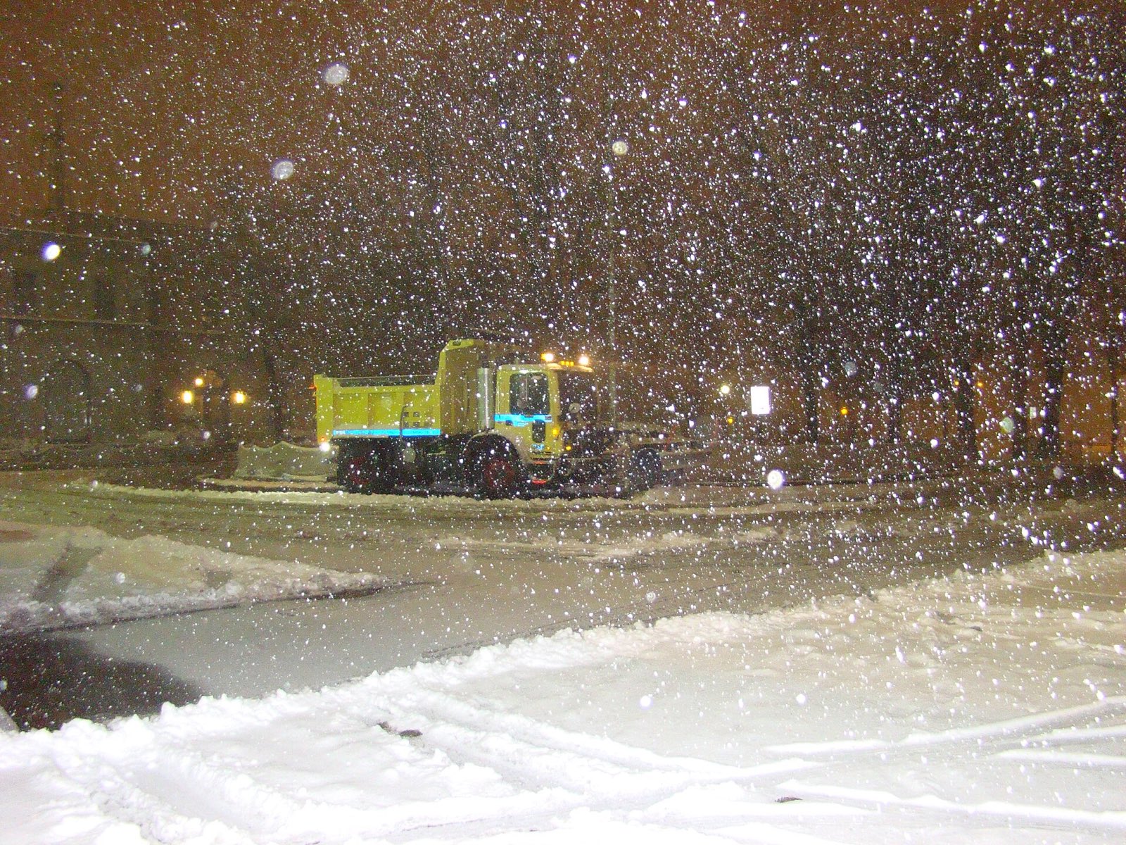 Plow truck clearing an empty lot in the dark